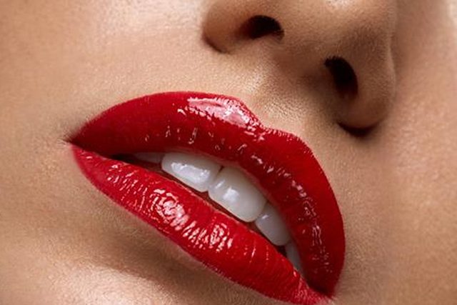 A closeup of a woman's lips wearing red lipstick.